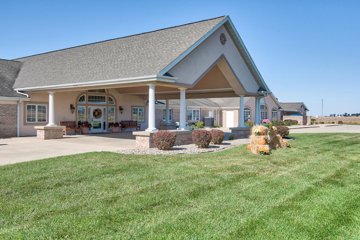 A single-story building with a gabled roof surrounded by a well-manicured lawn on a clear day.
