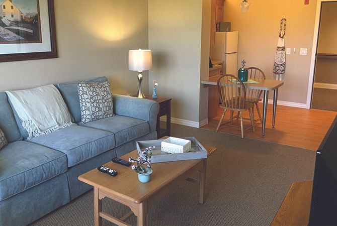 A cozy living room with a blue sofa, coffee table, and adjacent dining area leading to a kitchen.