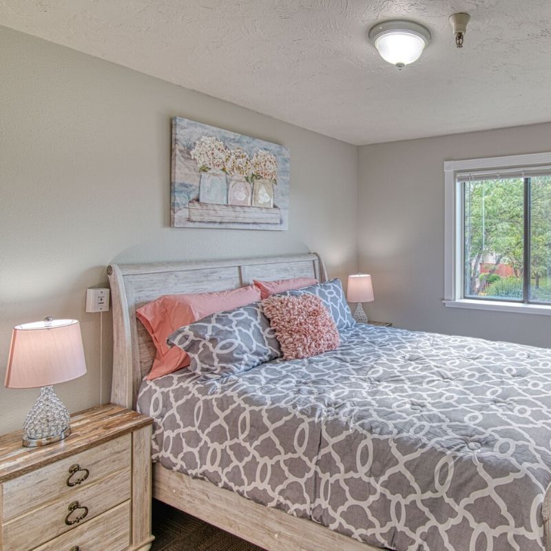 A cozy bedroom with neatly arranged bedding and soft lighting from bedside lamps.