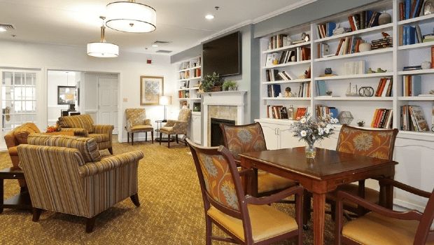Cozy living room with bookshelves and a fireplace, featuring comfortable seating and elegant decor.