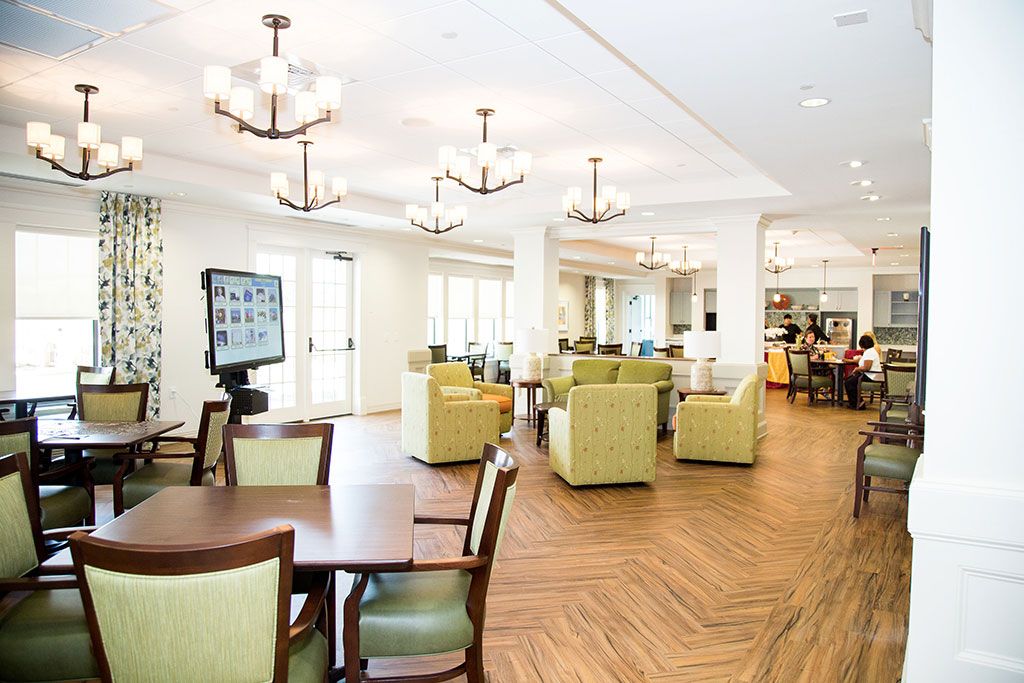 A spacious and modern lounge area with comfortable seating, adorned with chandeliers and wooden flooring.