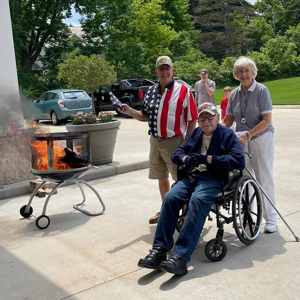 A group of people enjoying a barbecue outdoors, with one person in a wheelchair wearing patriotic clothing.