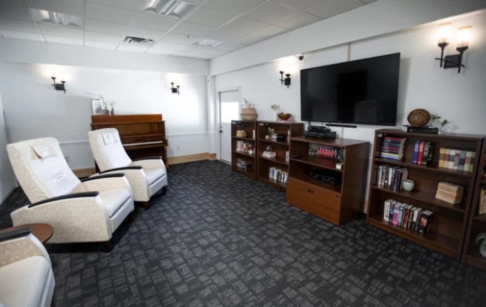 A cozy living room with a piano, bookshelves, and comfortable seating.
