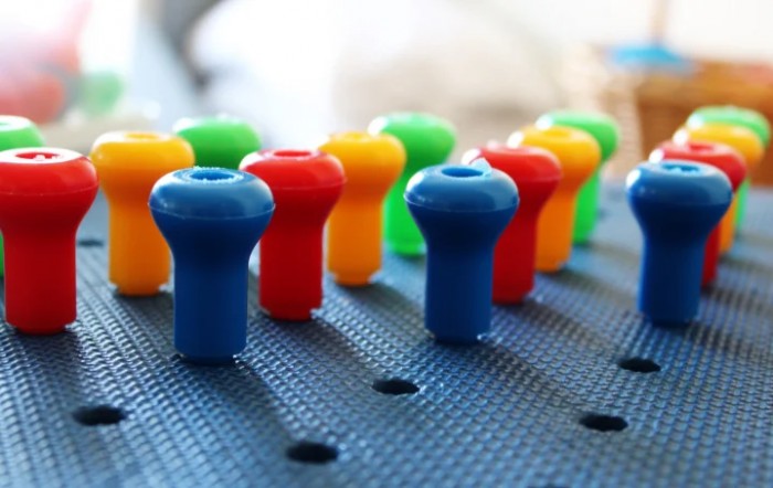 Close-up of colorful plastic pegs on a perforated board.