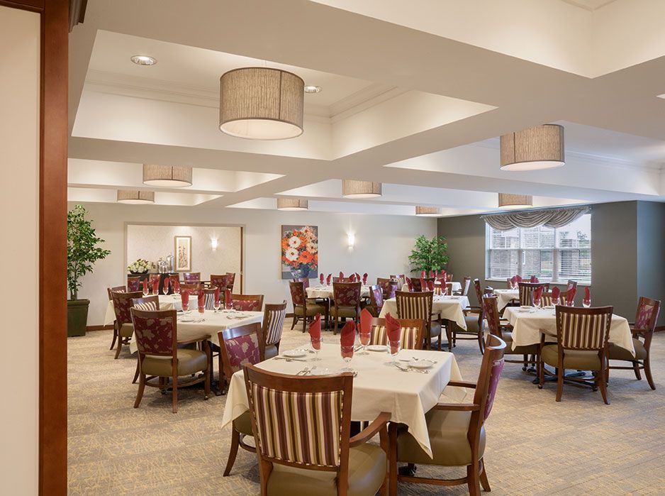 An elegant restaurant dining area with neatly arranged tables and chairs, featuring modern lighting fixtures.
