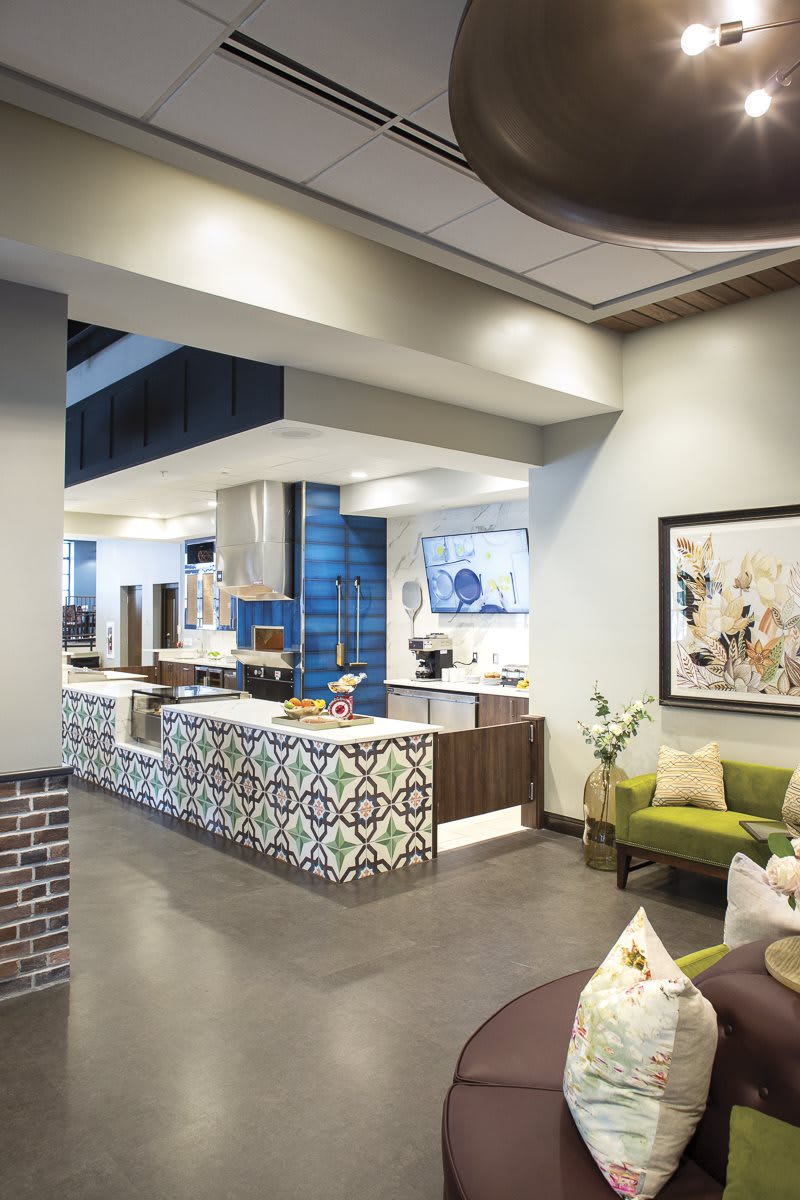 A modern cafe interior featuring decorative tiled counters, comfortable seating, and contemporary artwork.