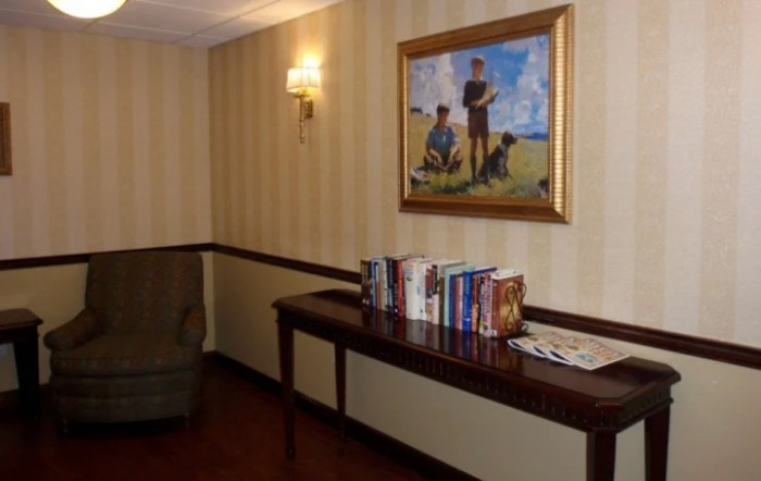 A cozy interior with a painting above a table lined with books.