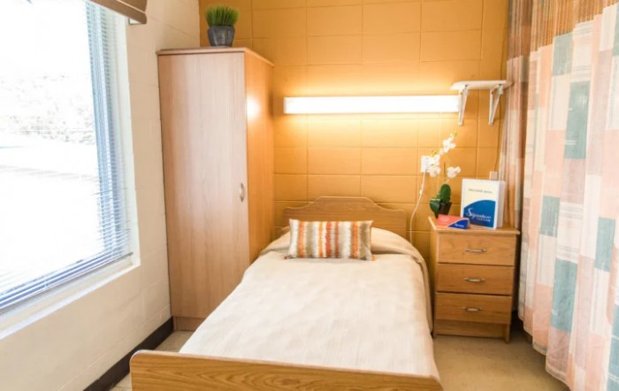 A cozy and minimalist bedroom with a single bed, wardrobe, and warm lighting.