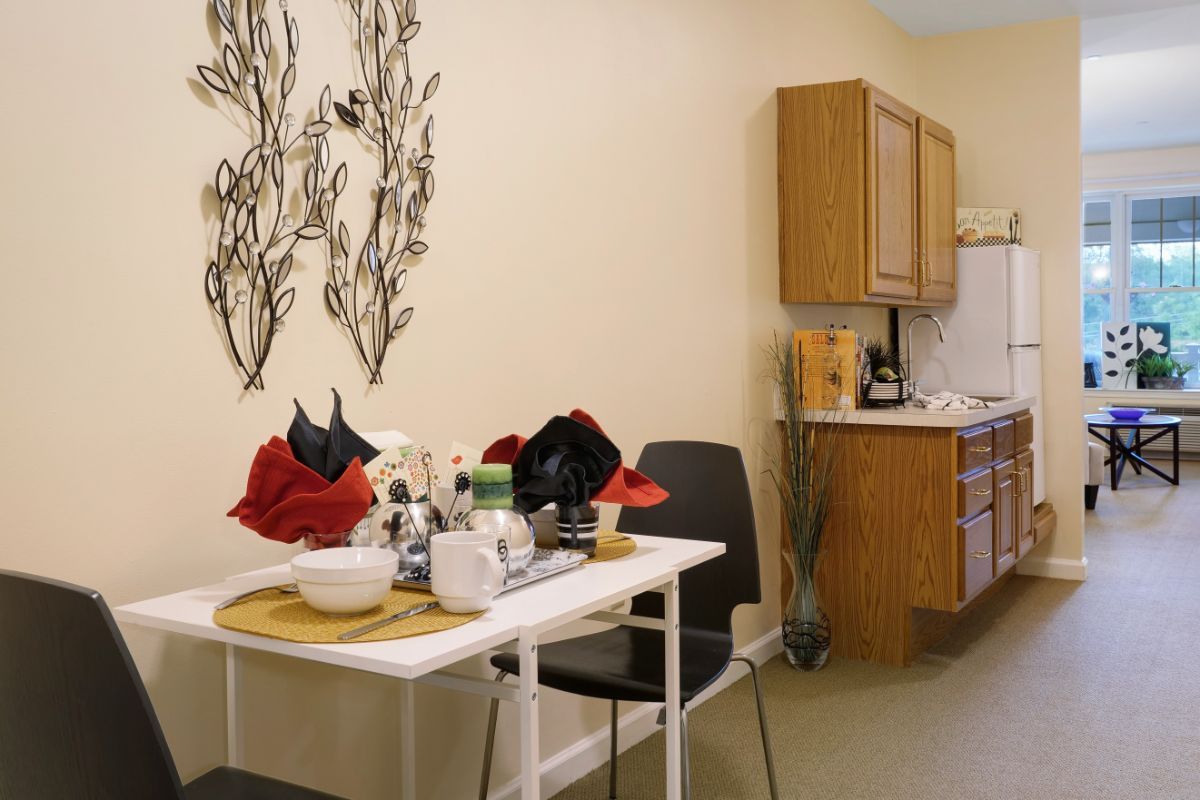 A cozy kitchen dining area with a small table, chairs, and decorative wall art.