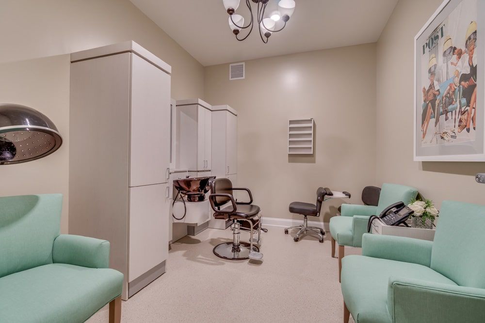 A salon room with chairs and white cabinetry under a stylish lighting fixture.