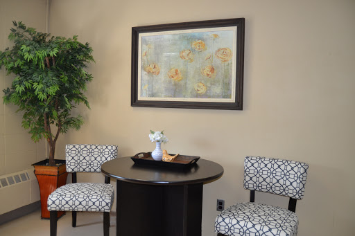 A cozy waiting area featuring stylish chairs, a circular table, and framed artwork.