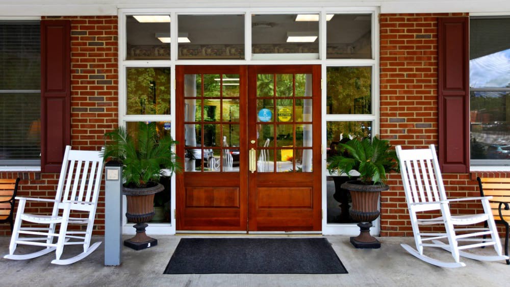 A symmetrical entrance with large wooden doors and glass windows, flanked by potted plants.