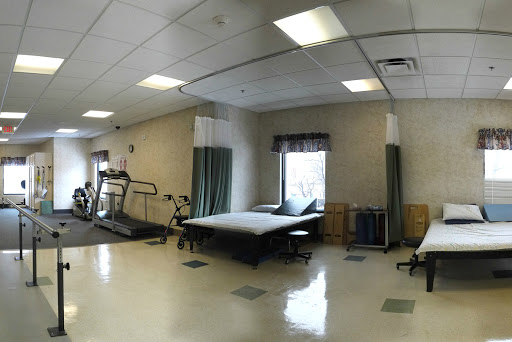A spacious rehabilitation room equipped with a treadmill and therapy beds, designed for physical therapy sessions.