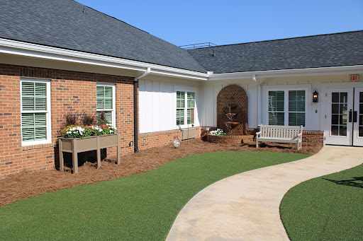 A serene outdoor space featuring a pathway, manicured lawn, and flower beds.