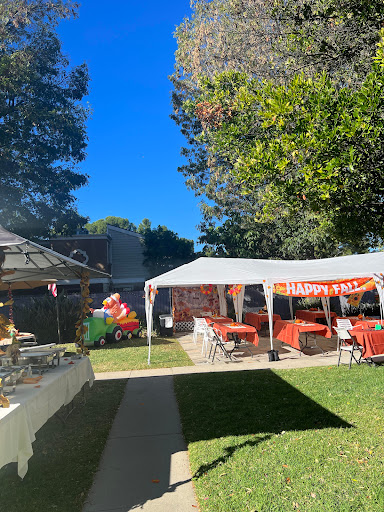 A festive outdoor party setup with a large tent and colorful decorations under a clear blue sky.