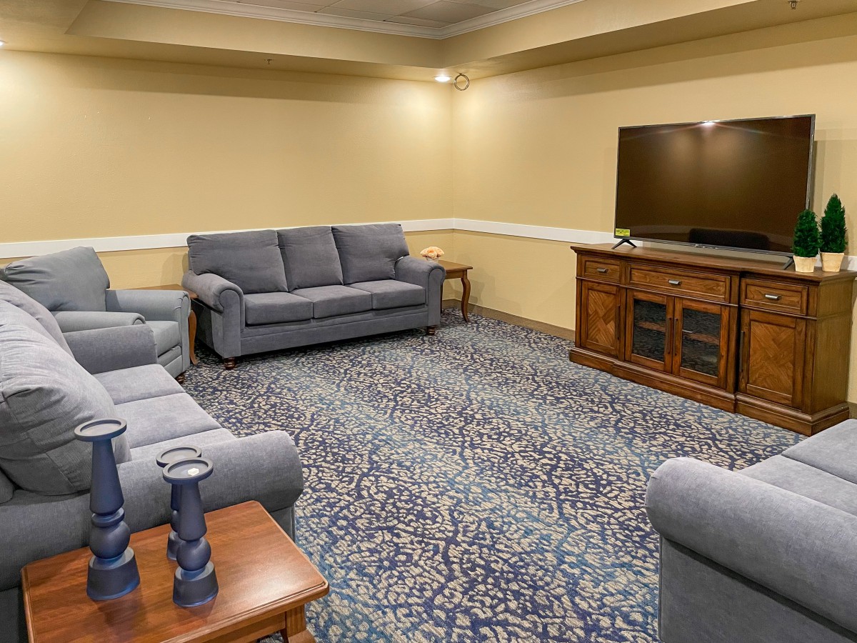A cozy living room with blue sofas and a flat-screen TV on a wooden stand.