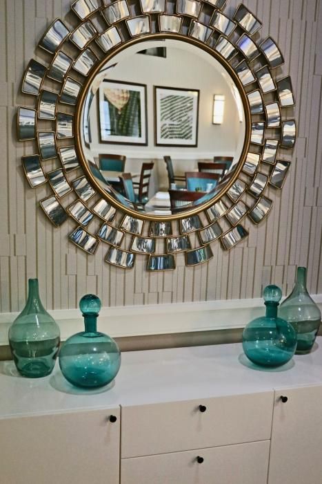 A stylish interior featuring a decorative round mirror surrounded by blue glass vases.