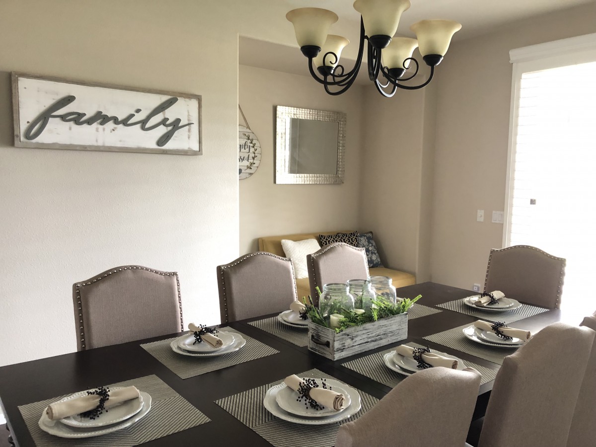 A modern dining room with a neatly arranged table setting and elegant chandelier.