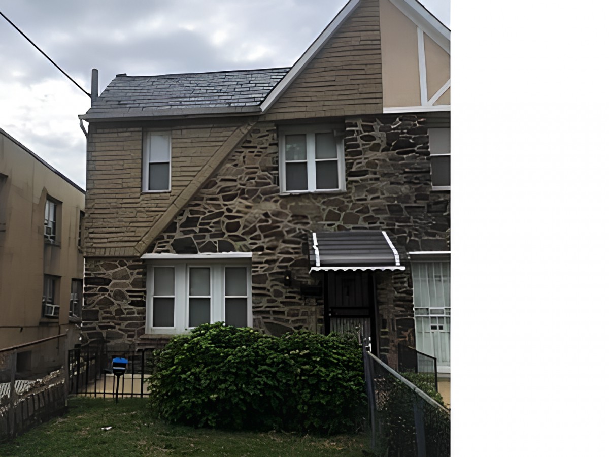 A residential house with a stone facade and a small front yard.