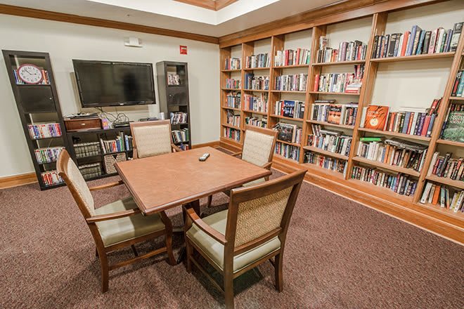 A cozy library reading room with a table and chairs surrounded by bookshelves.