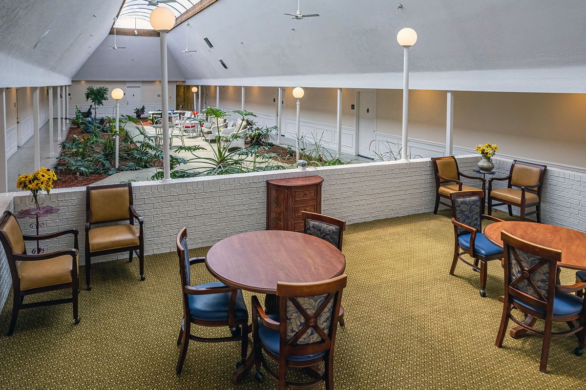 A cozy indoor seating area with tables and chairs overlooking a well-lit space.