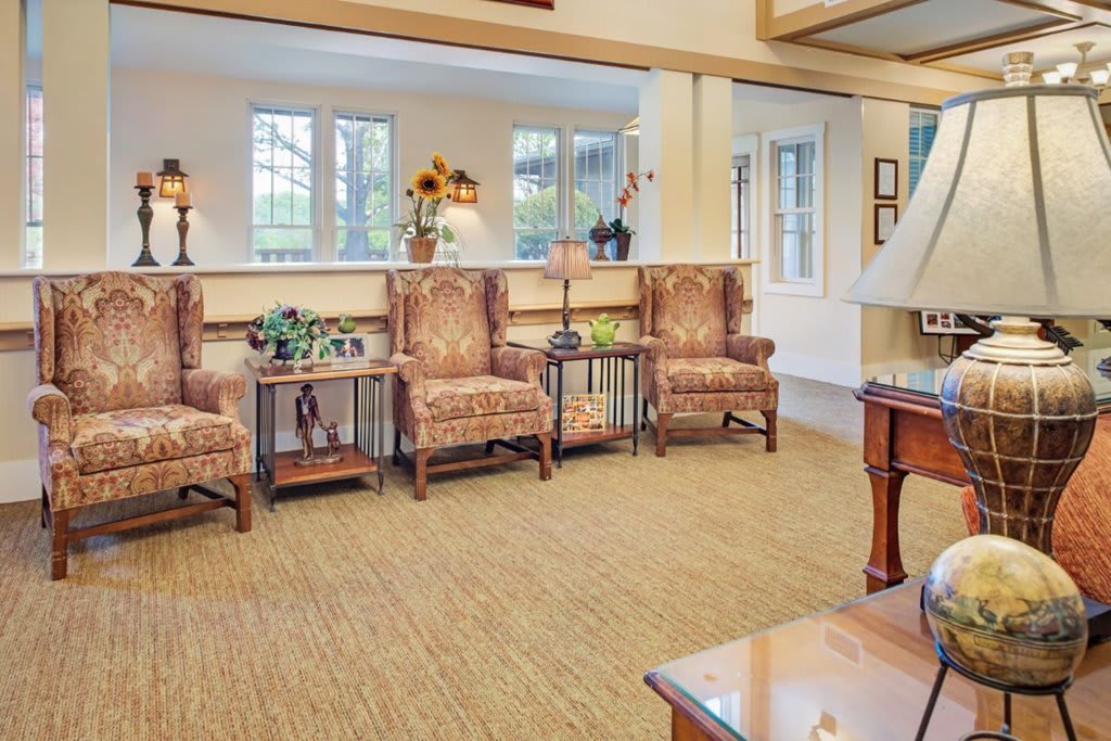 A traditionally styled living room with cozy chairs and large windows.