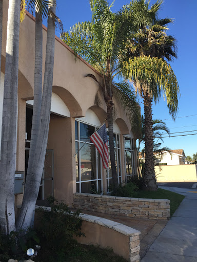 A view of a building adorned with palm trees and an American flag under a clear blue sky.