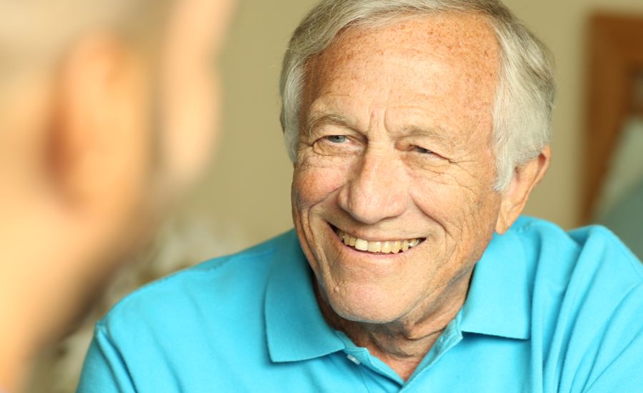 An elderly man smiling in a casual setting.