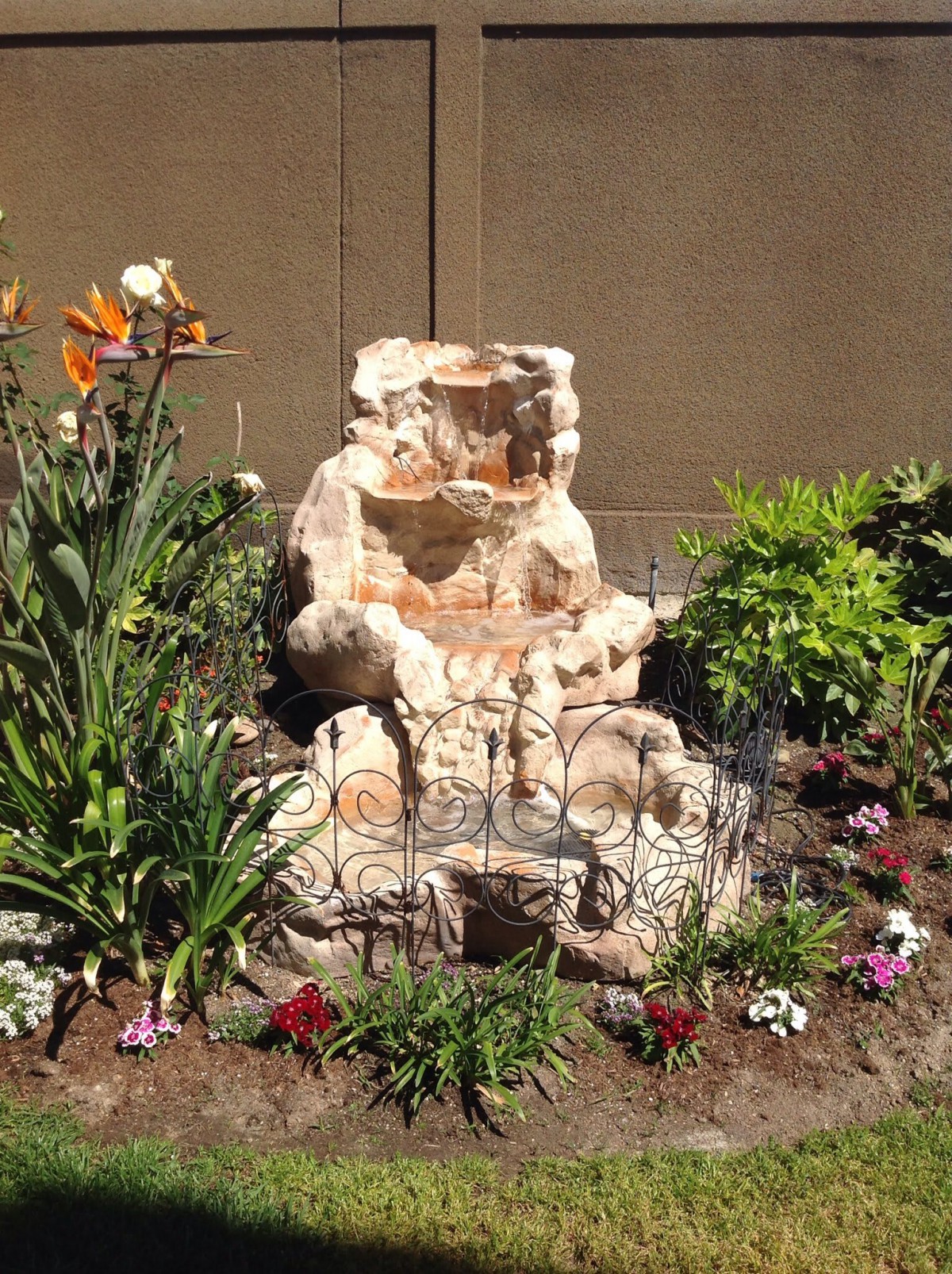 A beautifully arranged garden landscape featuring a rock formation surrounded by a variety of flowers and plants.