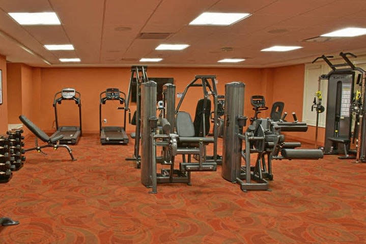 A gym interior with various exercise machines and an orange-themed decor.