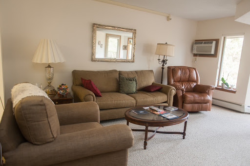 A cozy living room setup featuring a comfortable sofa, an armchair, and a coffee table adorned with magazines.