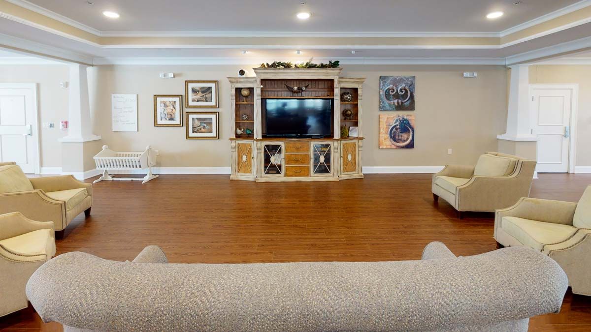 A spacious living room featuring an entertainment center with a TV, wooden flooring, and comfortable sofas.
