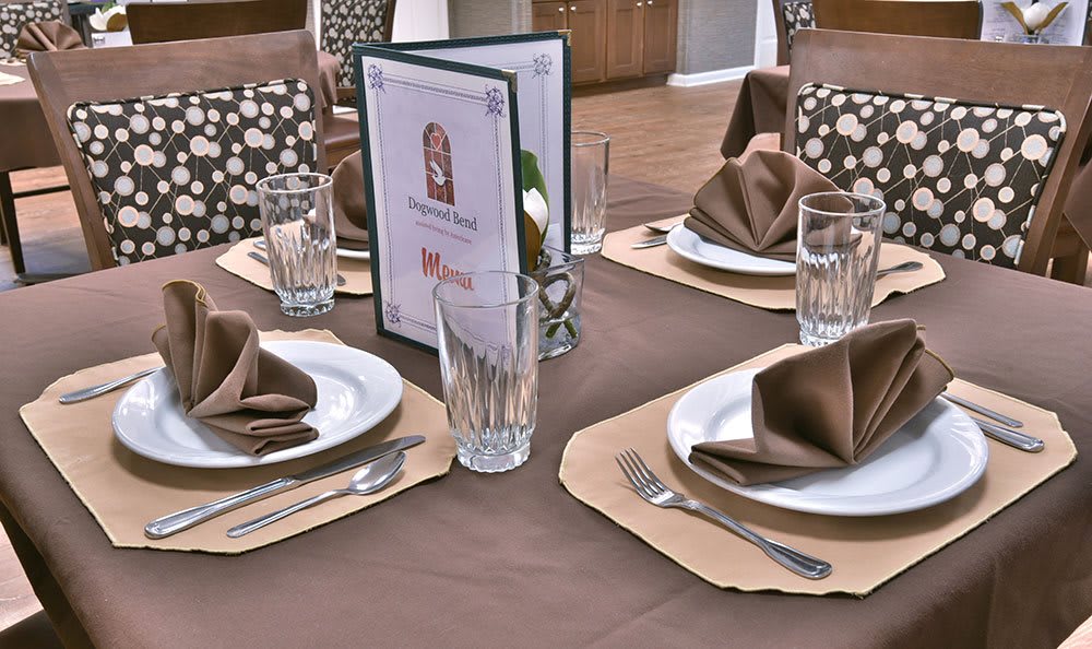 An elegant table setting with neatly folded napkins, glasses, and a menu at a restaurant.