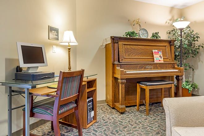 A cozy room featuring a wooden piano and a computer desk with seating.