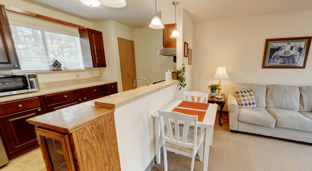 A cozy kitchen and dining area with wooden cabinets and a small dining table set for two.