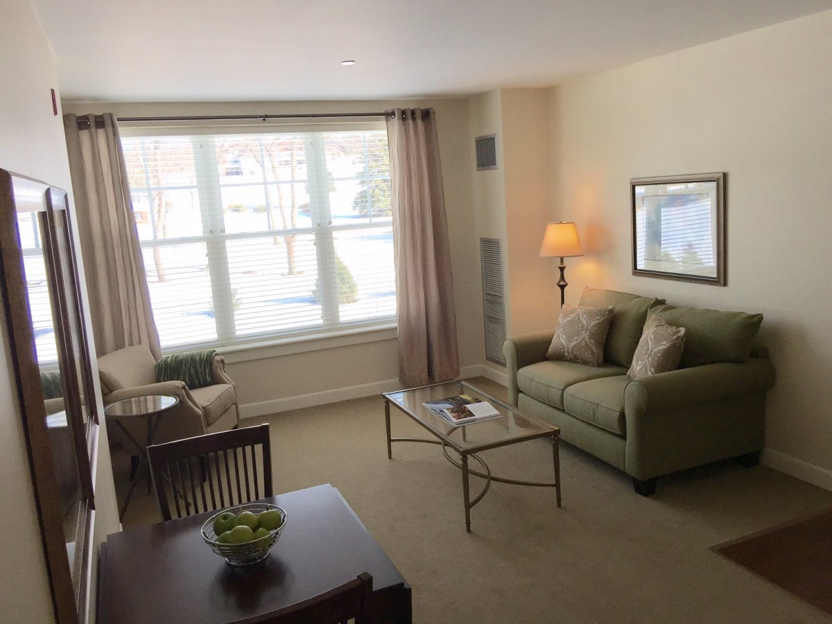 A cozy living room with a comfortable sofa, coffee table, and large window allowing natural light.