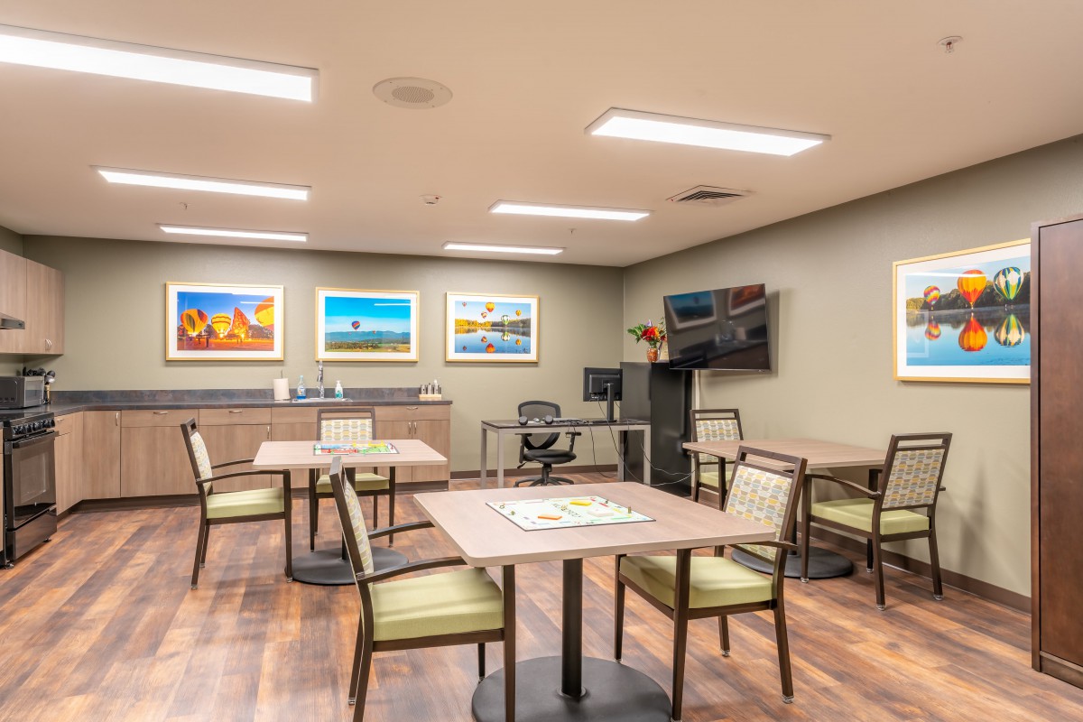 A modern meeting room with tables, chairs, and colorful artwork on the walls.