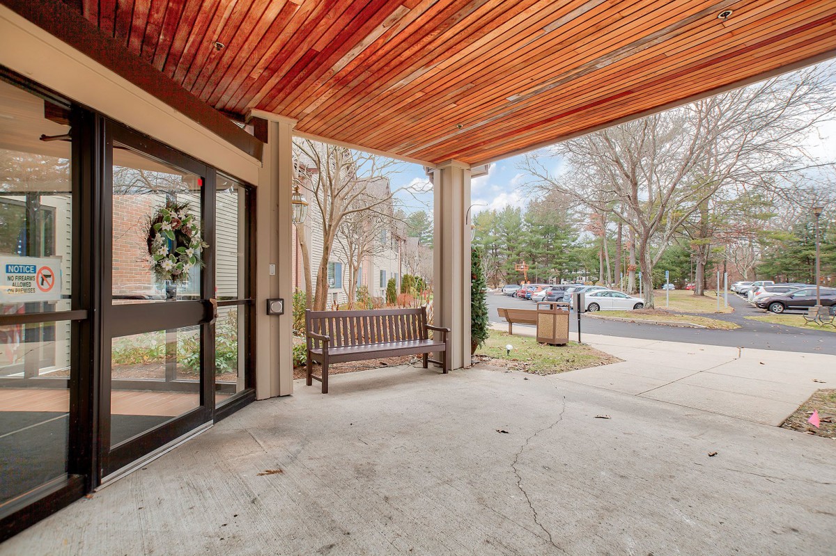 Outdoor building entrance with a wooden canopy and benches.