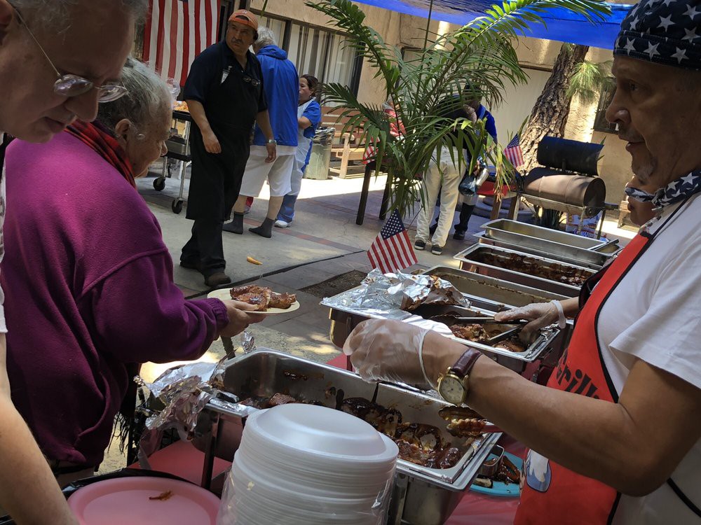 People are serving themselves food at a buffet during an outdoor event.