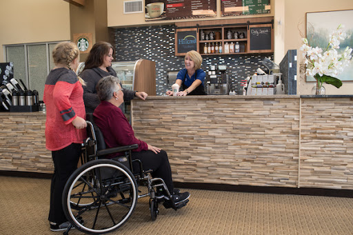 A group of customers interacting with a staff member at a caf, with one person in a wheelchair.