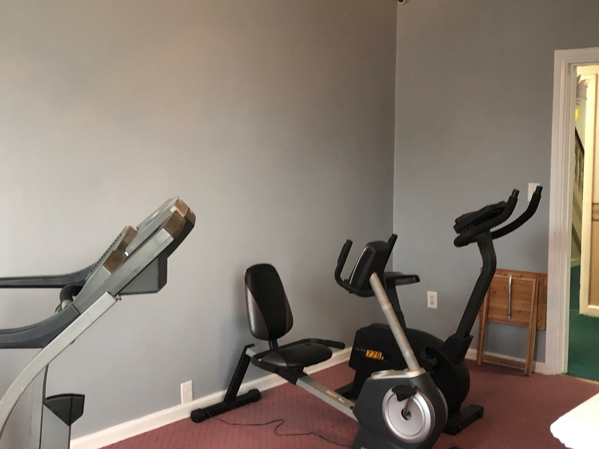 Home gym setup with stationary bike and rowing machine.