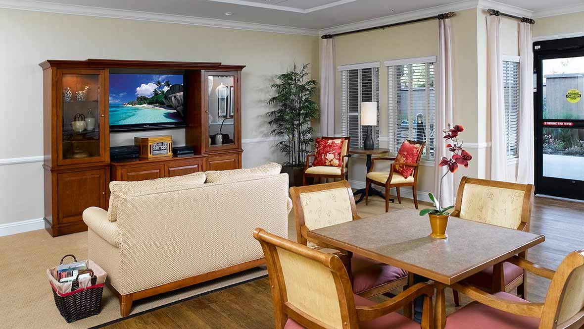 A cozy living room with a dining area featuring comfortable furniture and a large television.