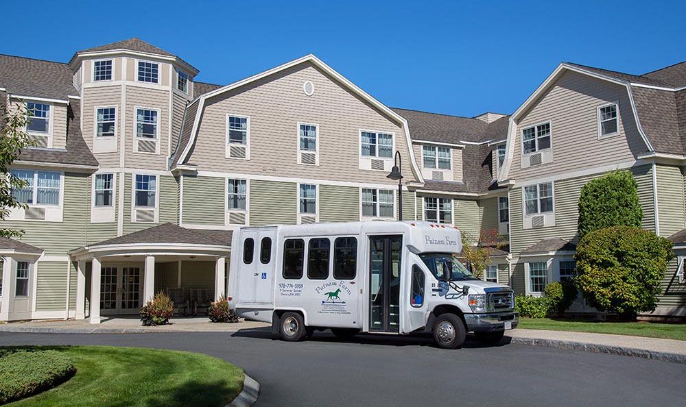 A small shuttle bus parked in front of a multi-story residential building.