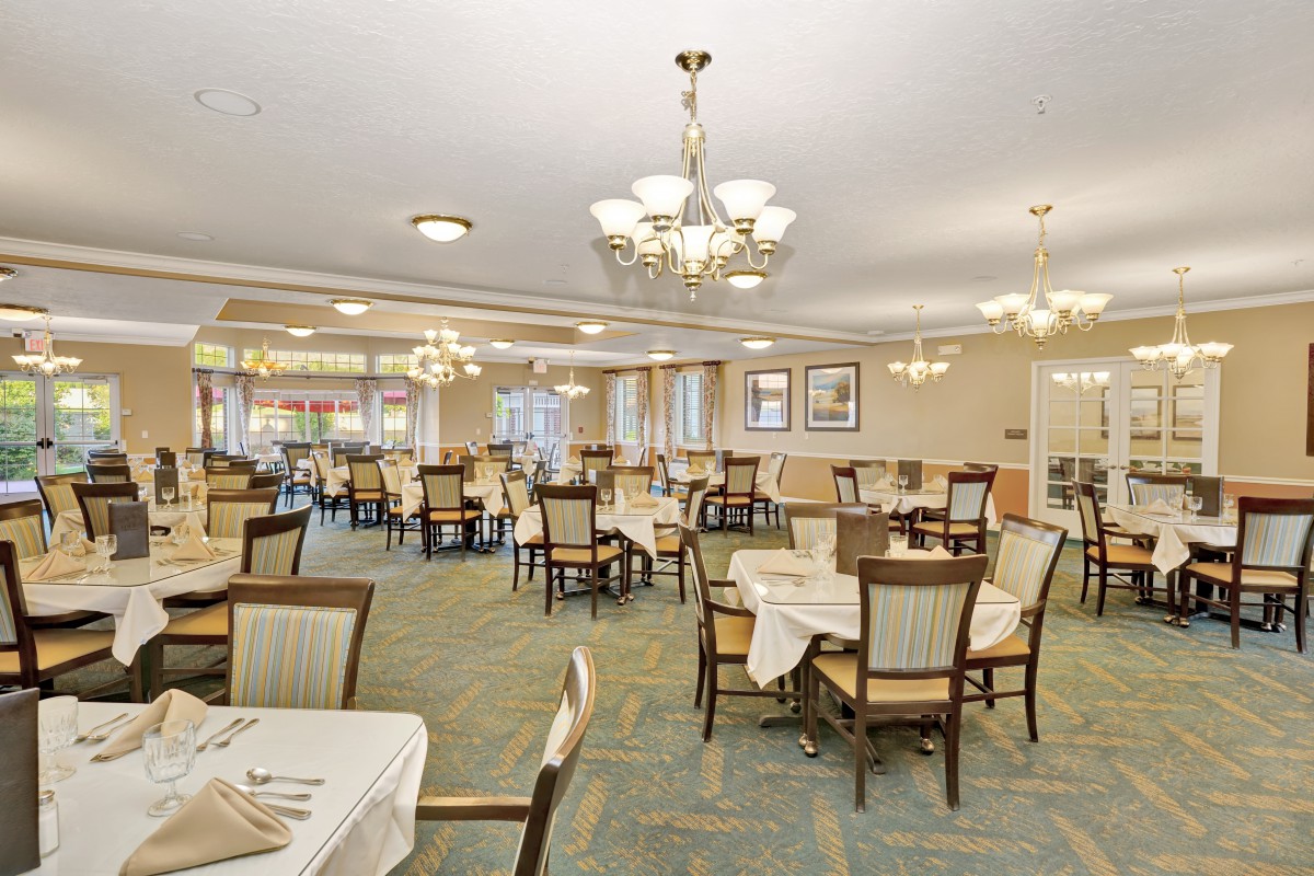 An elegant dining room with neatly arranged tables and chairs under stylish chandeliers.