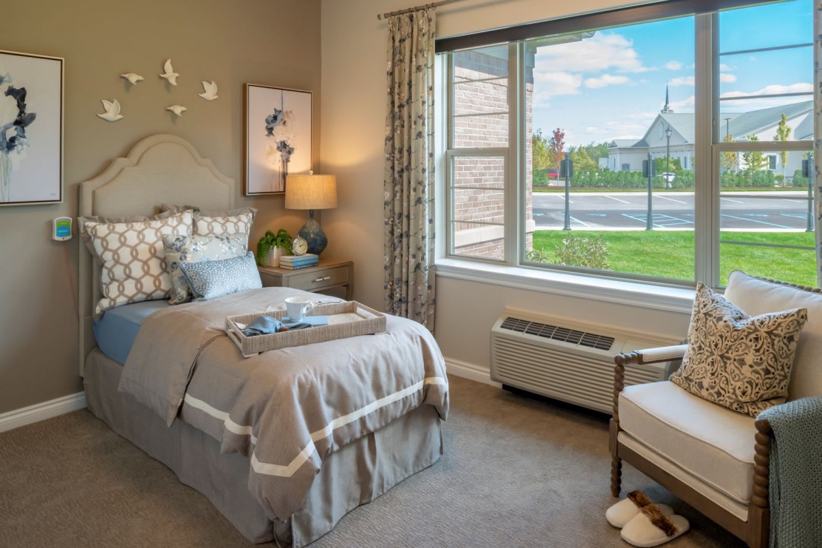 A cozy bedroom with a single bed, stylish decor, and a large window offering a scenic view.