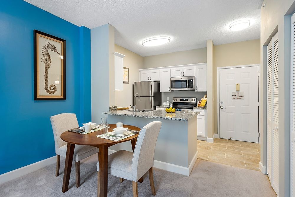 A modern apartment featuring a compact kitchen and cozy dining area with contemporary furniture.