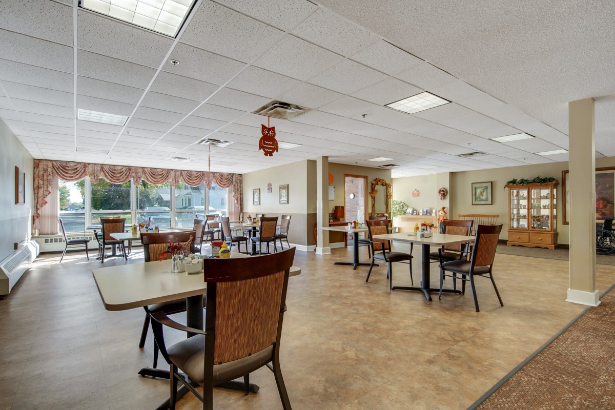 A spacious dining area with several tables and chairs, well-lit by ceiling lights and adorned with decor.
