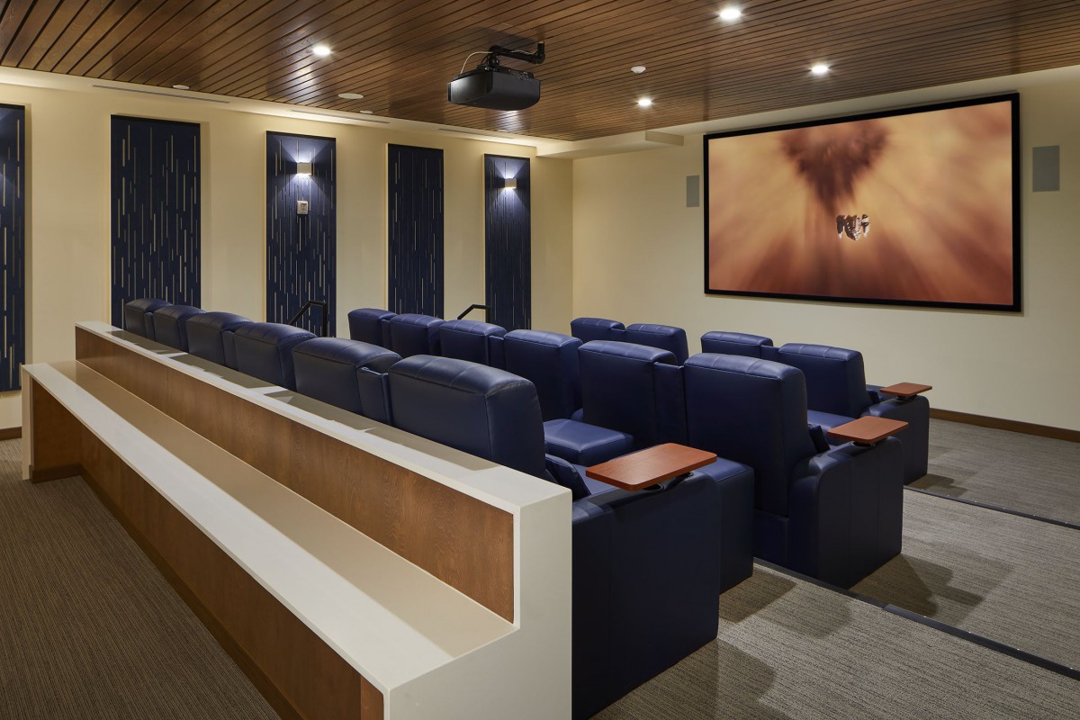 A luxurious home theater with multiple rows of comfortable seating and a large screen.