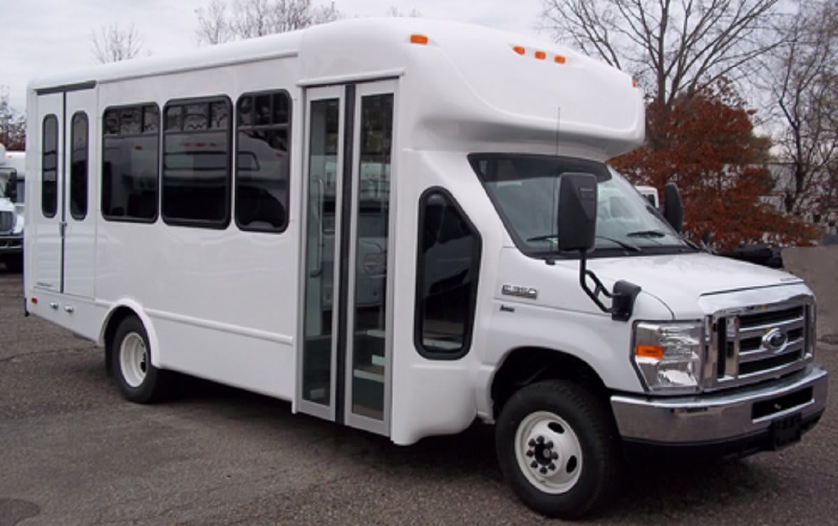 A white shuttle bus parked on a paved surface.