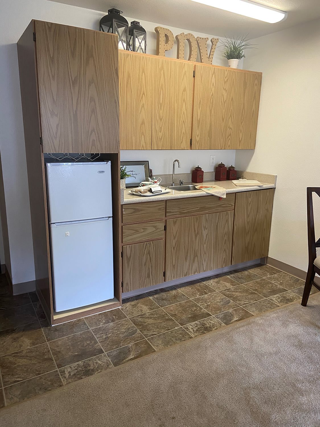 A small kitchen area with wooden cabinets and a refrigerator.